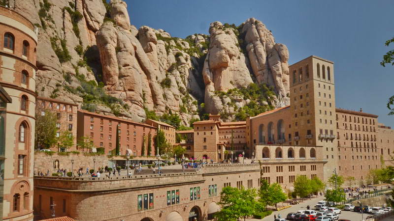 Historic monastery built into rugged mountain cliffs under a clear blue sky.