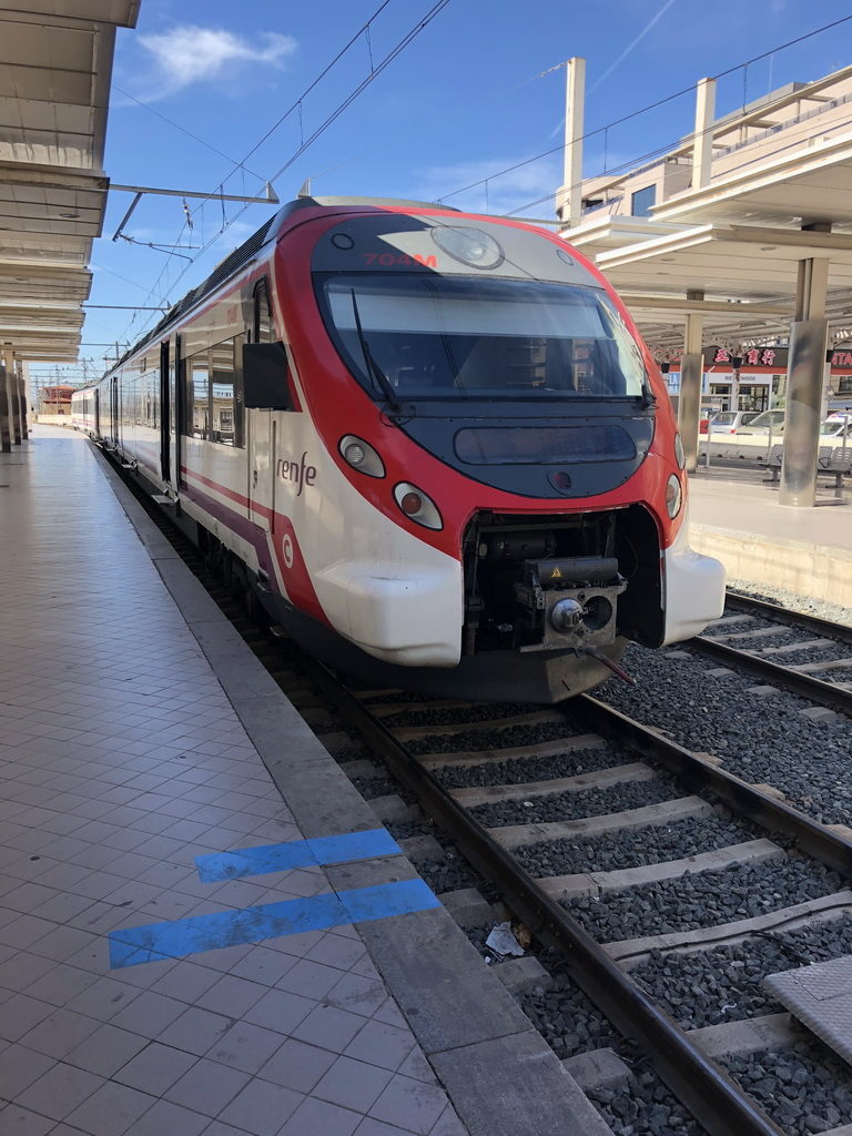 Modern red and white train at a station platform.
