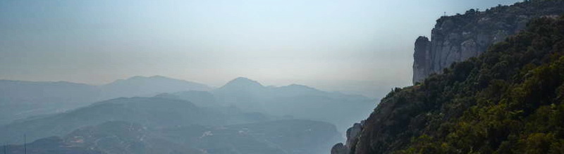 Mist-covered mountains under a pale sky.