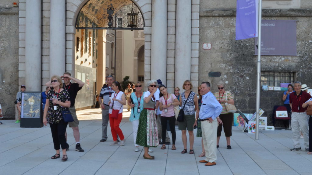 A group of tourists listens to a guide in a historic urban setting.