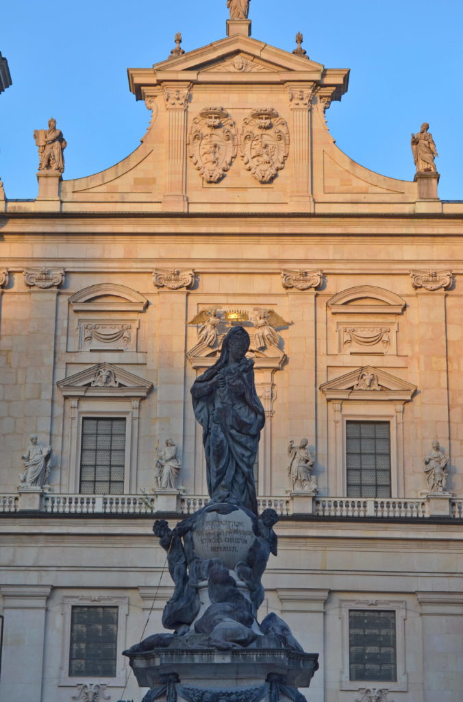 Statue silhouetted against a historic building at sunset.