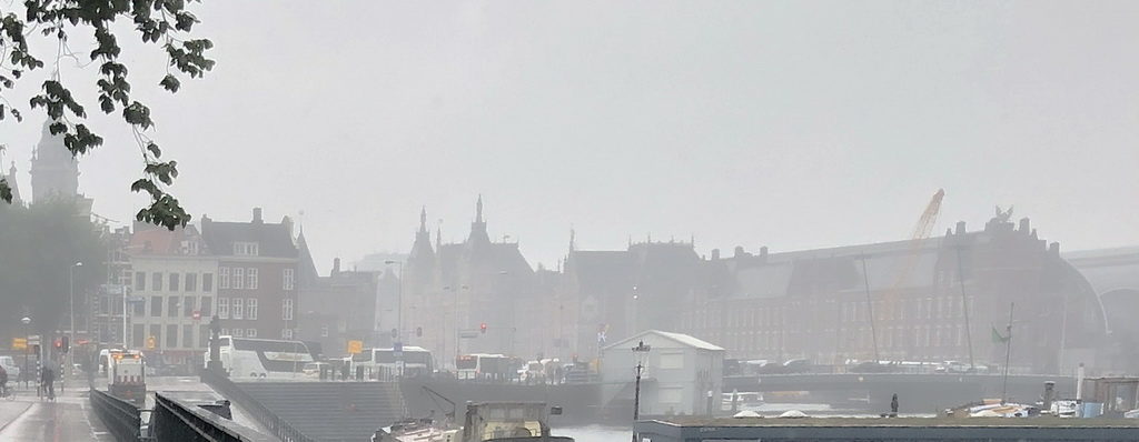 Foggy view of a historic city with gothic architecture and busy street traffic.