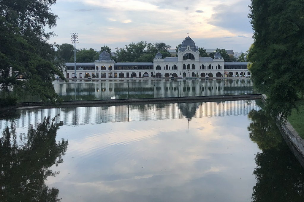 Elegant white building reflected in calm water under a cloudy sky.