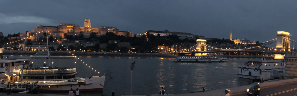 A nighttime river scene with illuminated buildings and a boat.