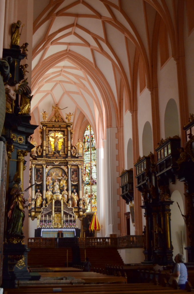 Interior of a historic church with ornate altar and high vaulted ceilings.