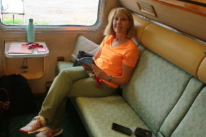 Passengers relaxing in a train's lounge car with drinks and casual seating.