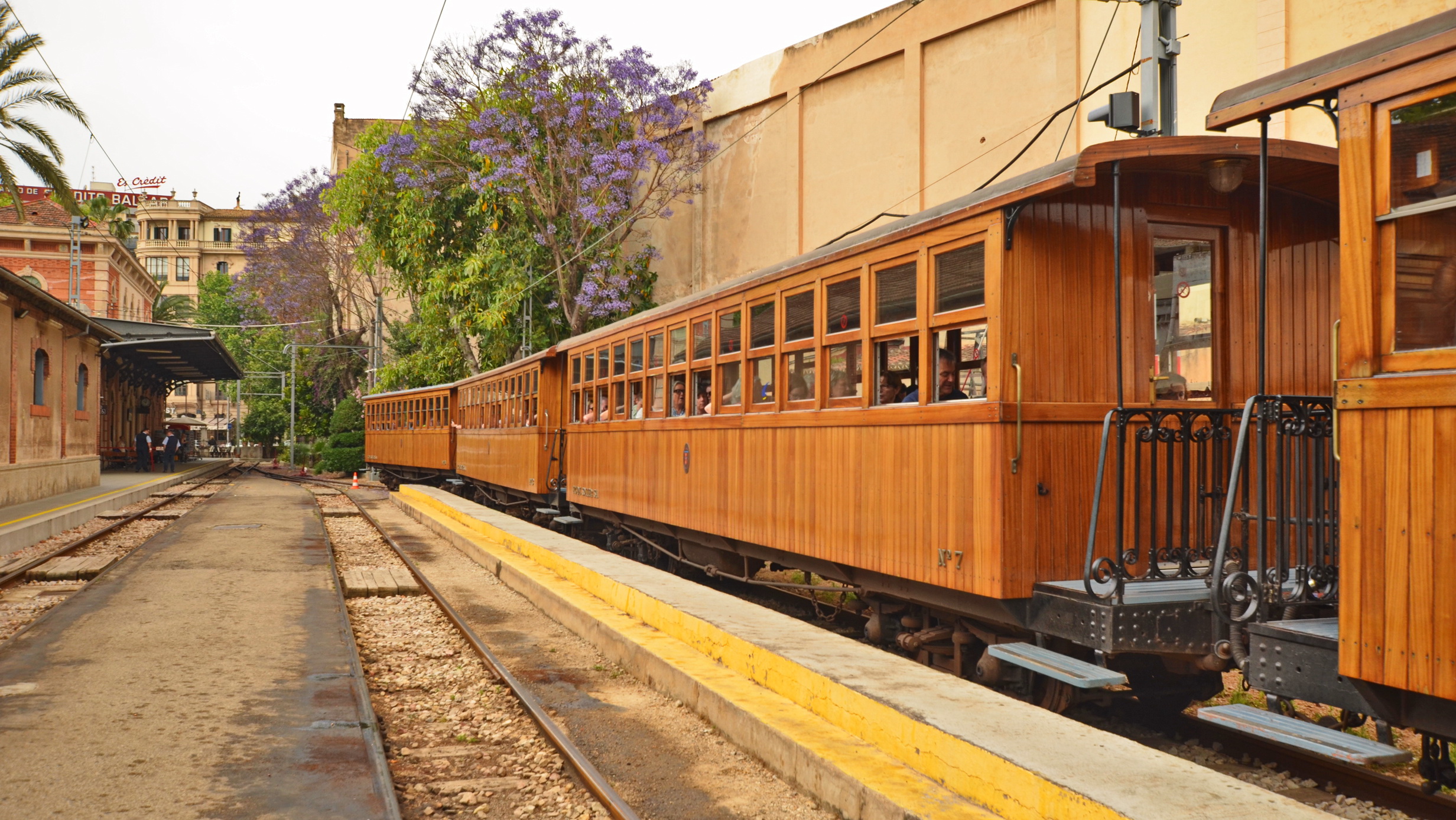 Historic wooden train carriages on railway tracks at a station platform.