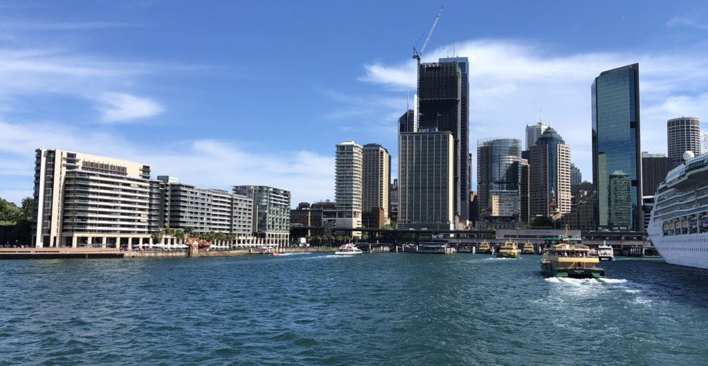 Modern city skyline with high-rise buildings near the water under a clear blue sky.