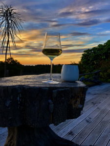 Wine glass and candle at sunset on wooden deck.
