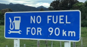 Blue road sign warning of no fuel for 90 km ahead.