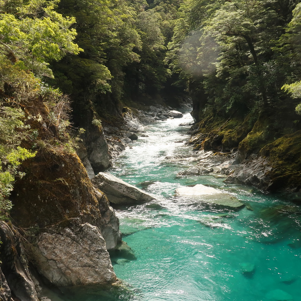 A clear turquoise river flowing through a rocky forested canyon.