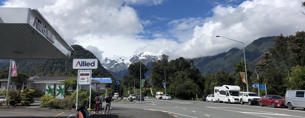 Scenic mountain road with snowy peaks and a clear blue sky.
