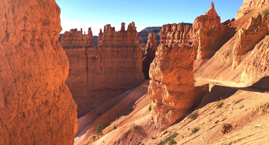 Scenic view of tall, layered red rock formations under a clear blue sky.