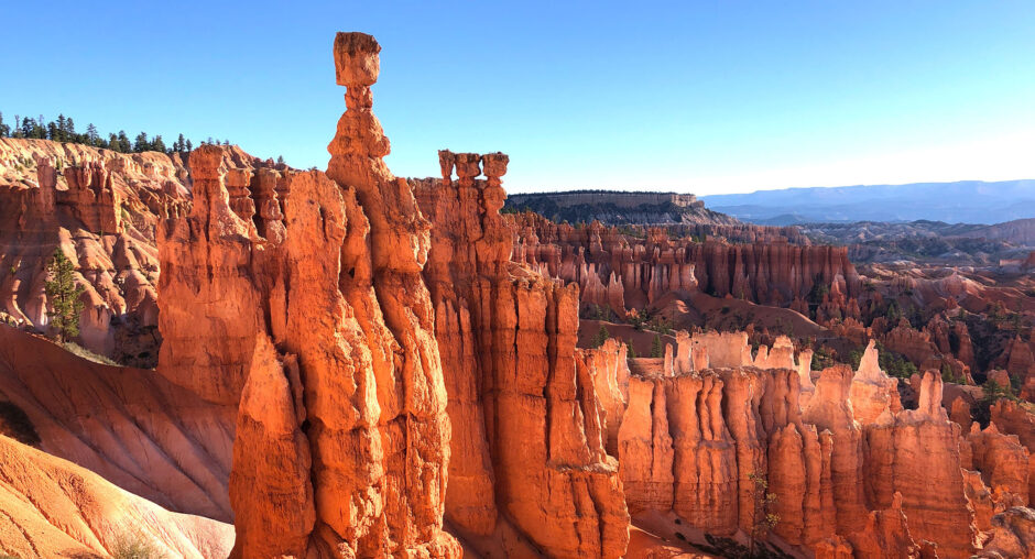 Red rock formations and hoodoos against a clear blue sky.