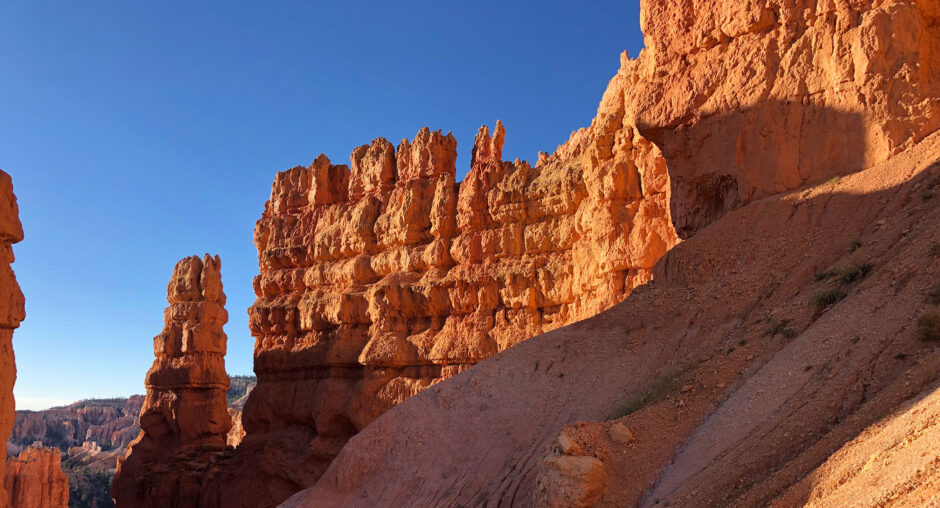 Sunlit red rock formations under a clear blue sky.