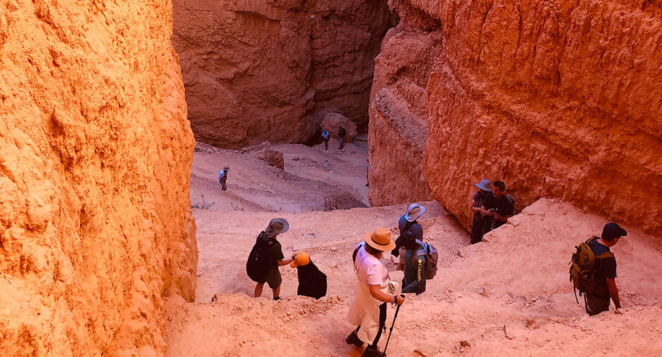 Tourists exploring a deep red canyon with steep walls.