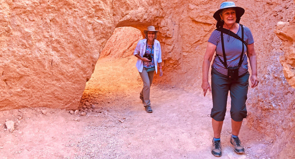 Two hikers exploring a rocky desert trail under a natural stone arch.