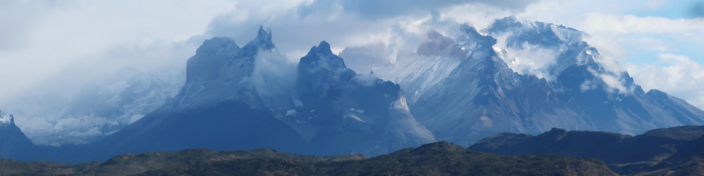 A lush green valley with a river flowing through mountainous terrain under a cloudy sky.