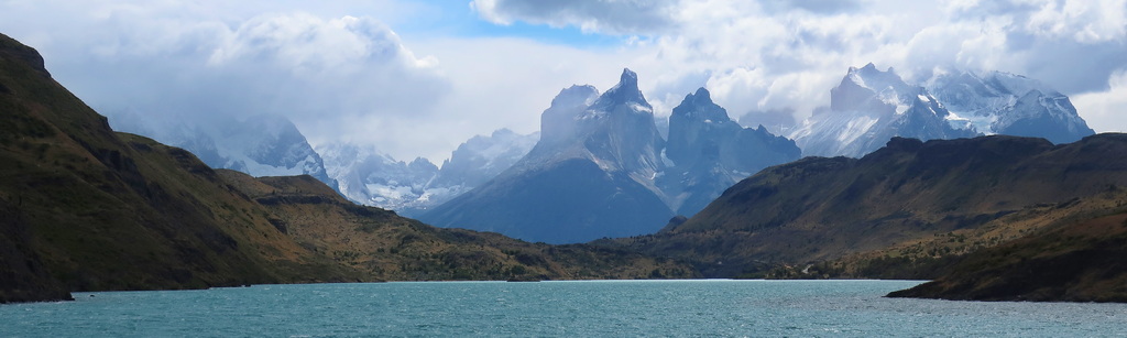 A lush green valley with a river flowing through mountainous terrain under a cloudy sky.