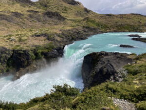 A lush green valley with a river flowing through mountainous terrain under a cloudy sky.