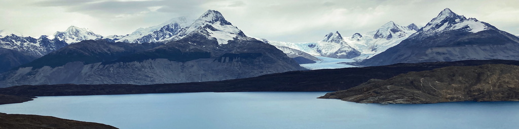 A lush green valley with a river flowing through mountainous terrain under a cloudy sky.