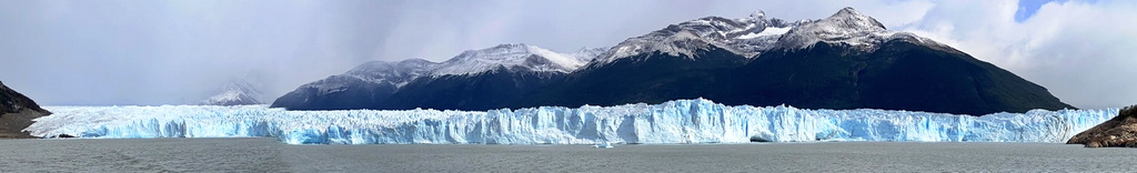 A lush green valley with a river flowing through mountainous terrain under a cloudy sky.