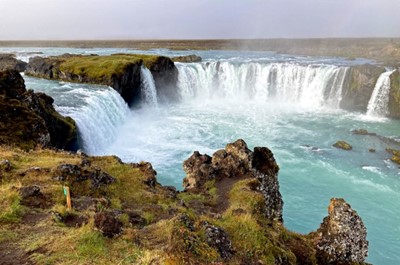 A powerful waterfall cascading over rocky cliffs into a turquoise pool.
