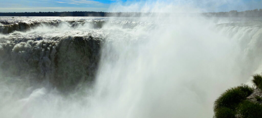 A lush green valley with a river flowing through mountainous terrain under a cloudy sky.