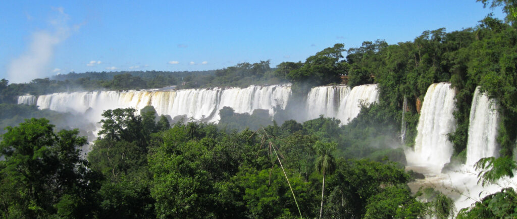 A lush green valley with a river flowing through mountainous terrain under a cloudy sky.