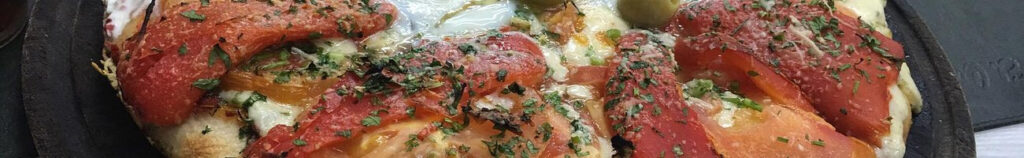 A lush green valley with a river flowing through mountainous terrain under a cloudy sky.