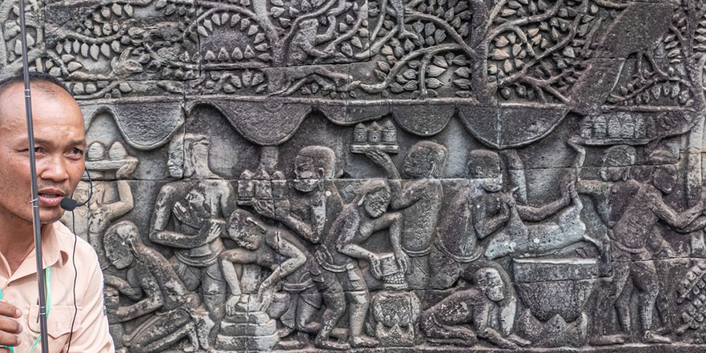 A lush green valley with a river flowing through mountainous terrain under a cloudy sky.