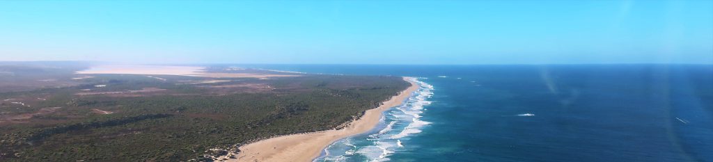 A lush green valley with a river flowing through mountainous terrain under a cloudy sky.